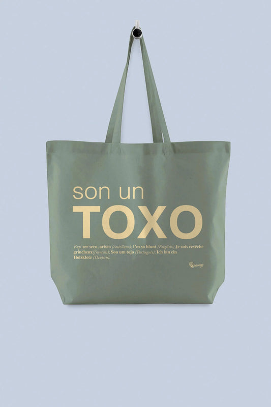 Tote bag grande verde oliva coa palabra "son un toxo" impresa, colgada dun percheiro